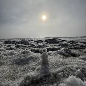 Snow man sitting on the sea ice